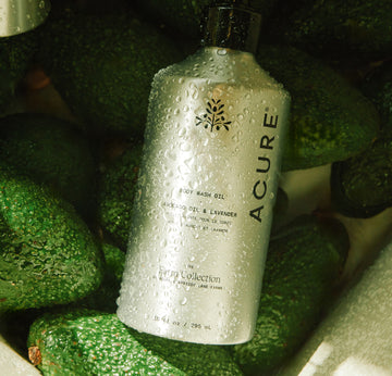 Acure body wash bottle on a bed of green avocados